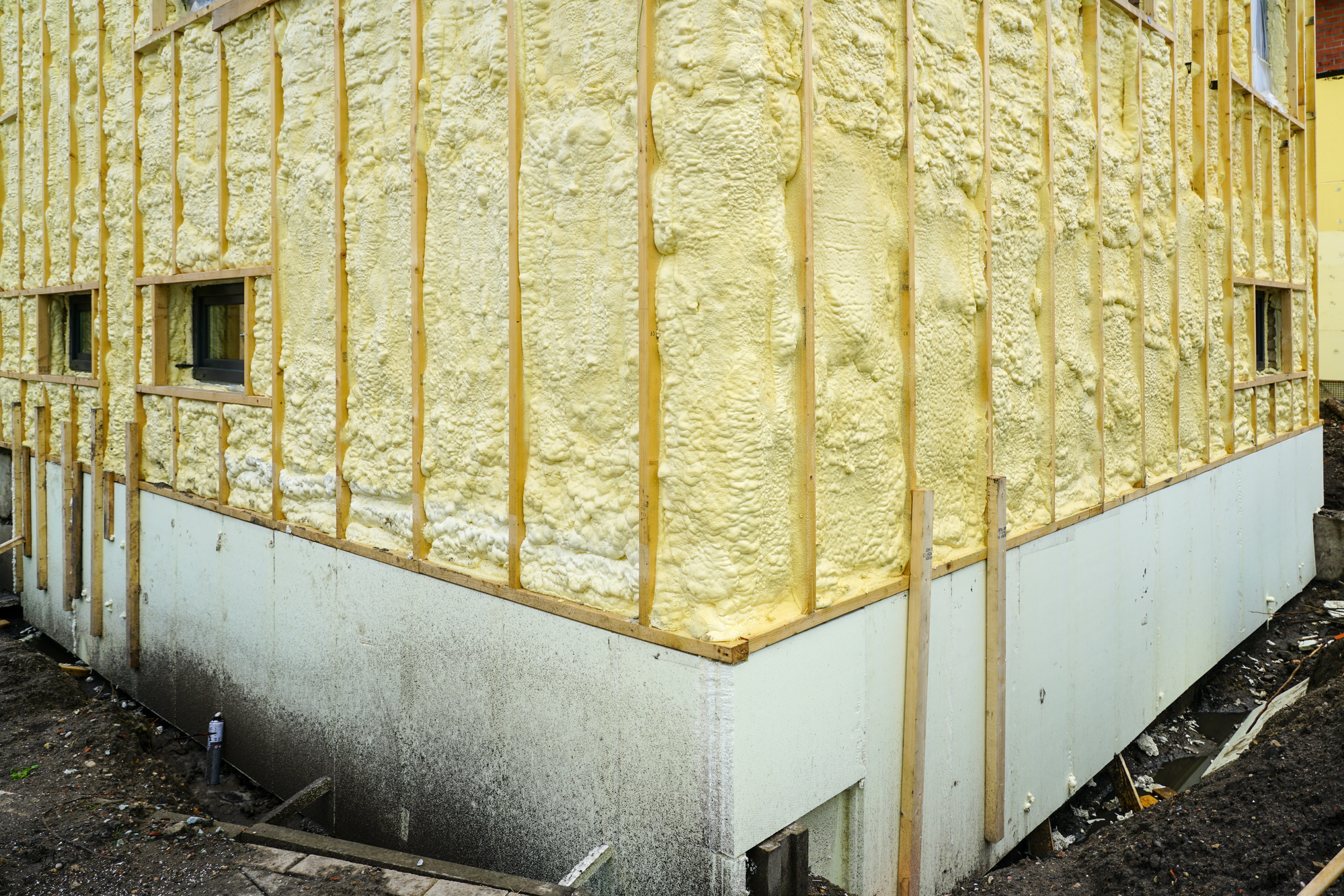 The facade of the residential house sprayed with a layer of polyurethane thermal insulation foam before siding, foundation insulation with foam boards